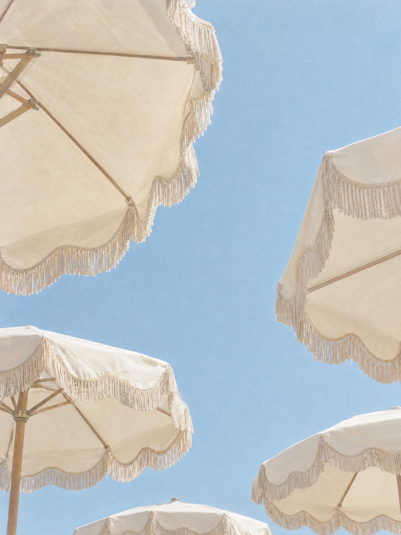 Cream beach umbrellas against a pale blue sky